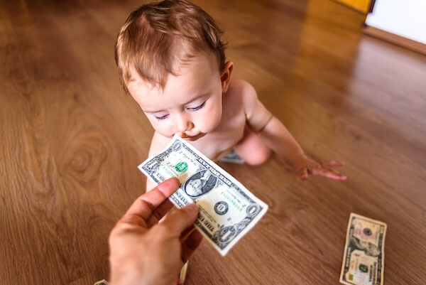 a baby sniffing a dollar bill preparing for the upcoming tax season